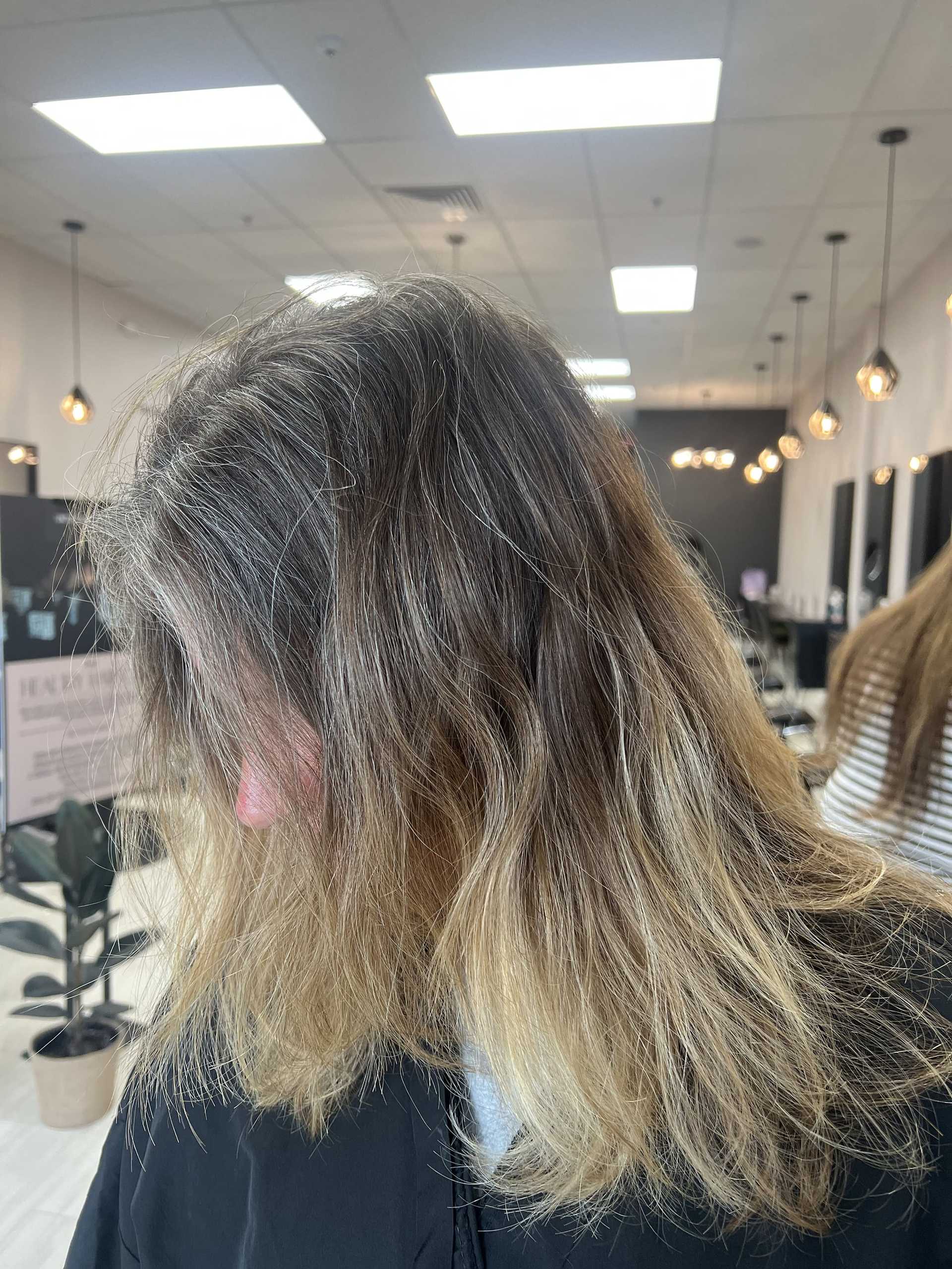 A woman with long, wavy blonde hair sits in a modern salon.