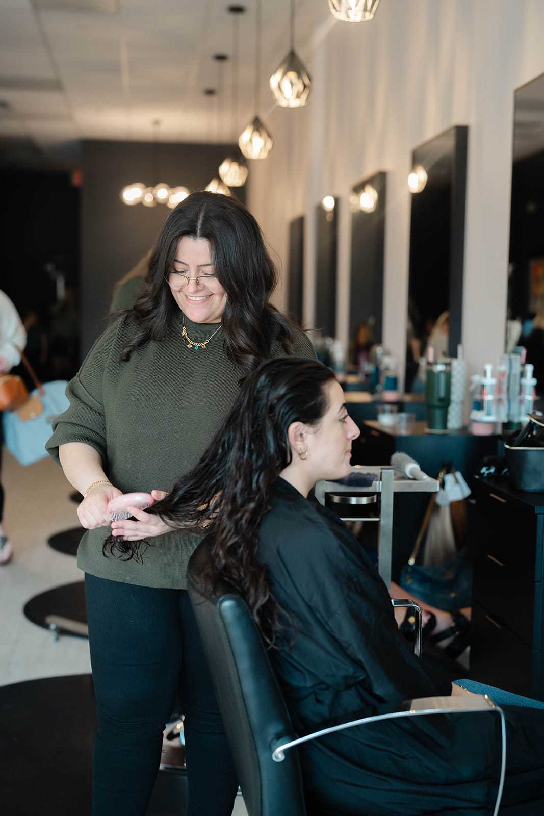 Hairstylist consulting with a client while preparing her long dark hair for a custom balayage