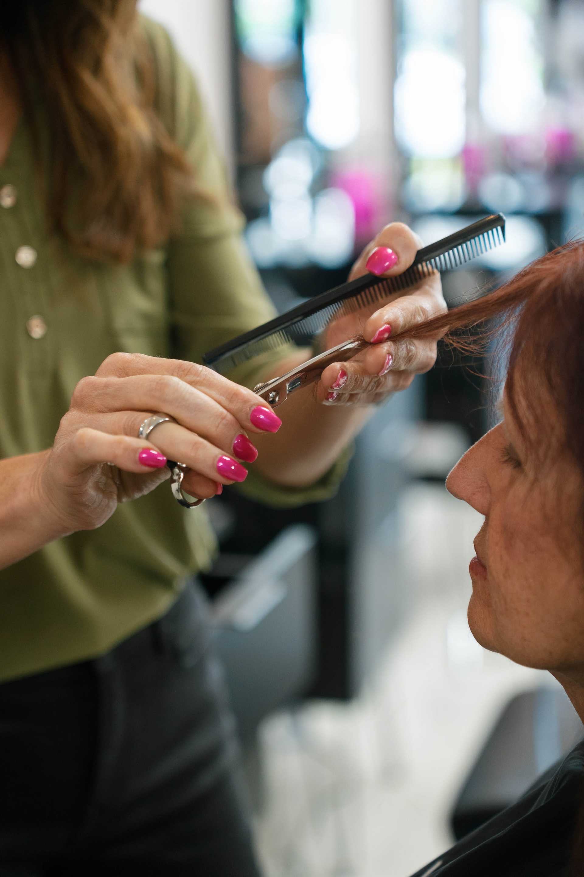 Hairdresser trims a client's hair in a salon with precision and care.