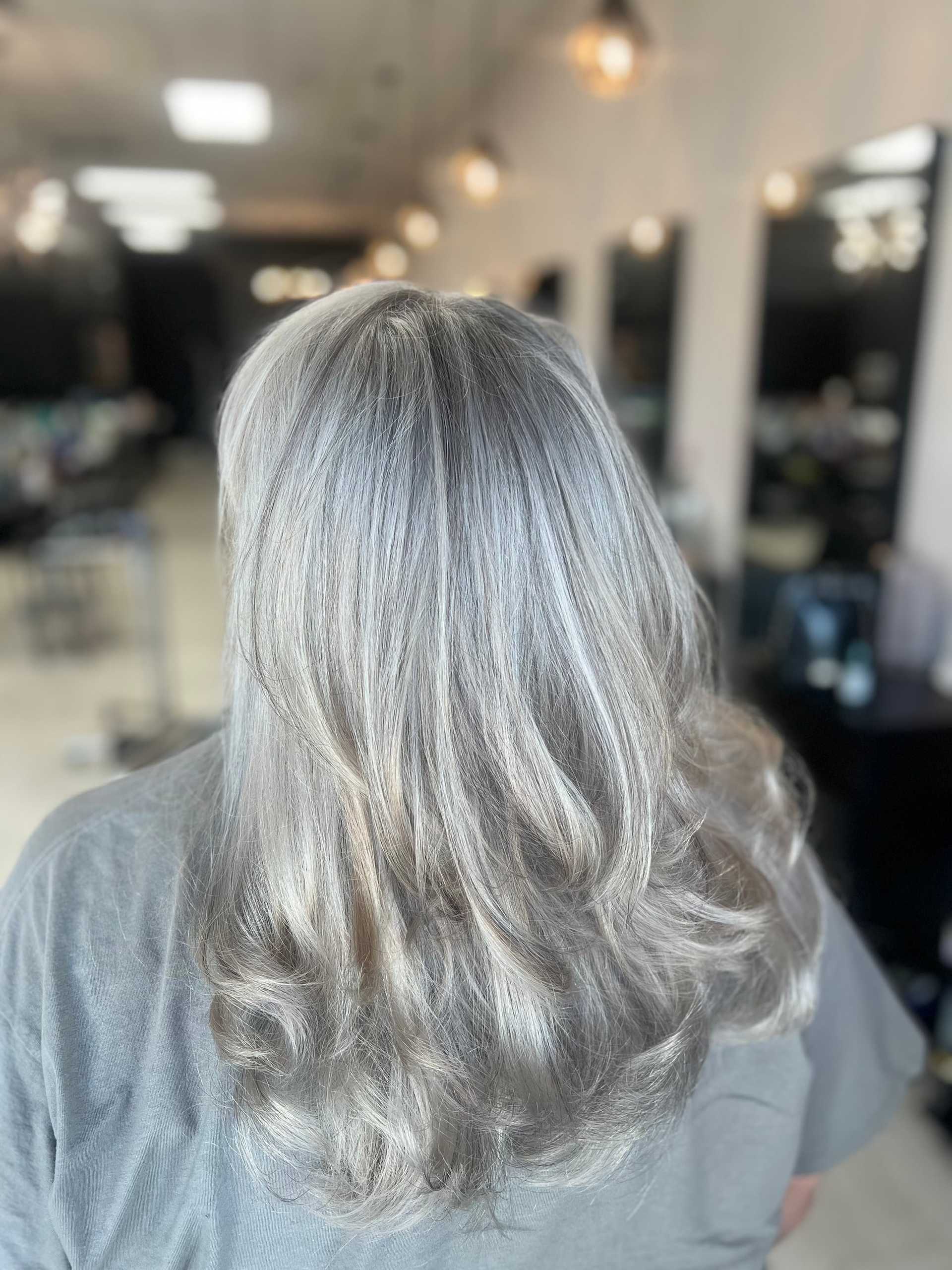 Wavy silver hair in a salon, styled with soft curls.