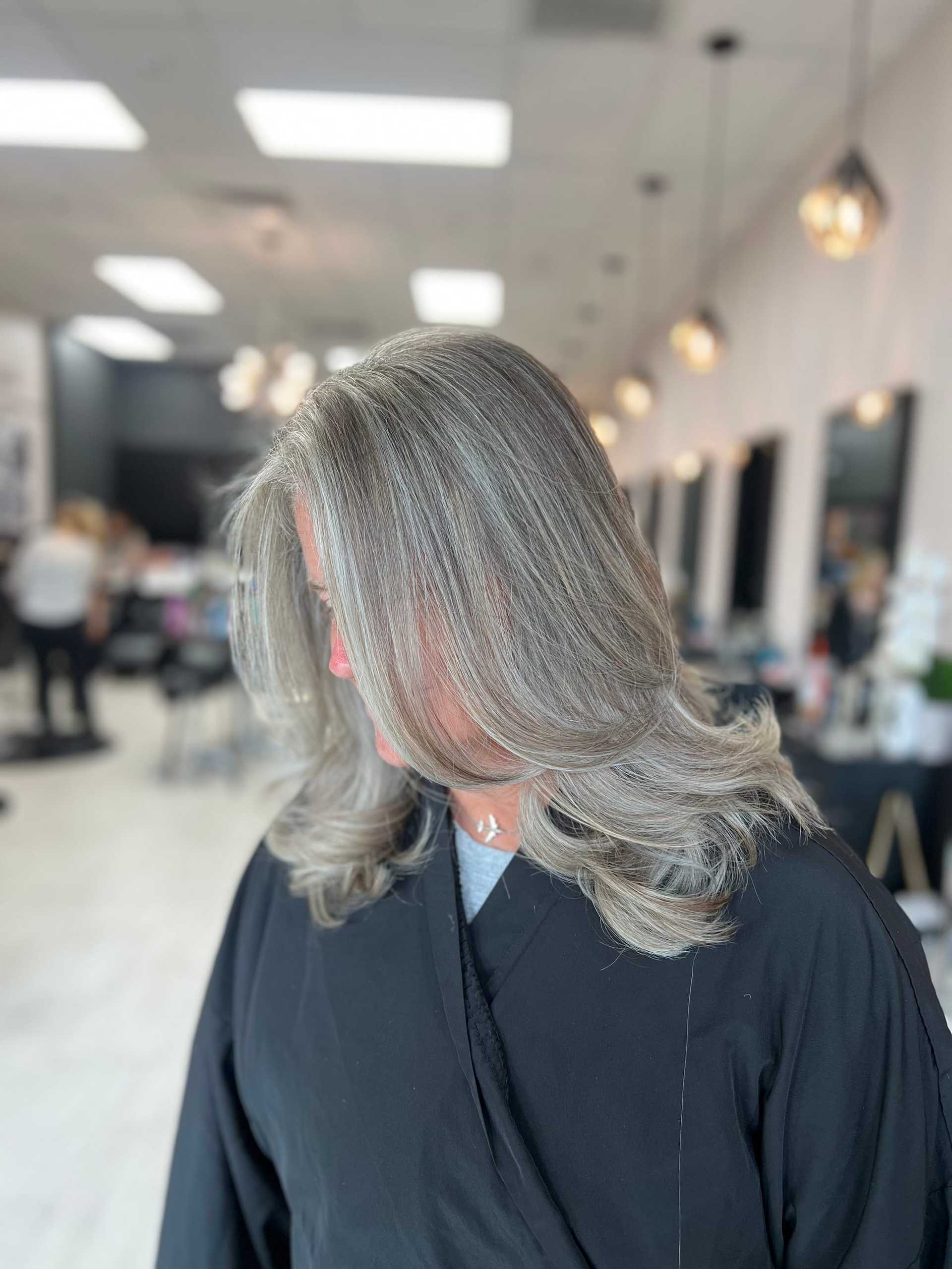 Woman with freshly styled gray hair in a salon setting.