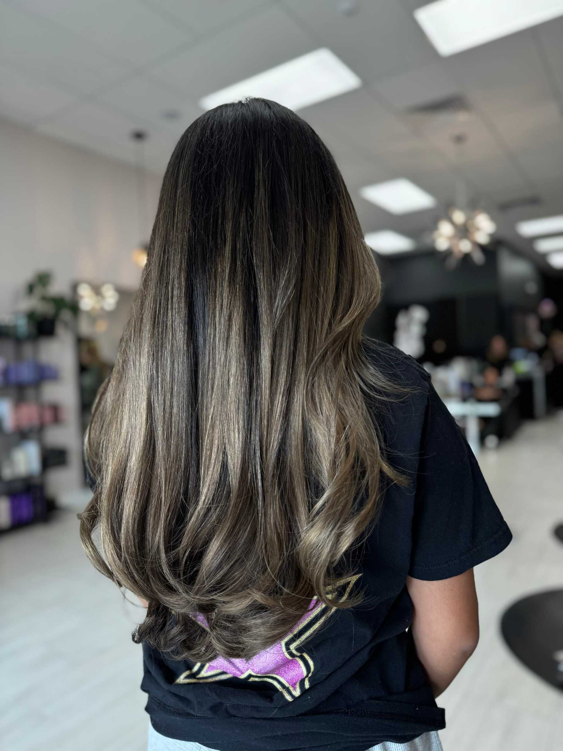 Long, wavy brown hair with highlights in a salon setting.