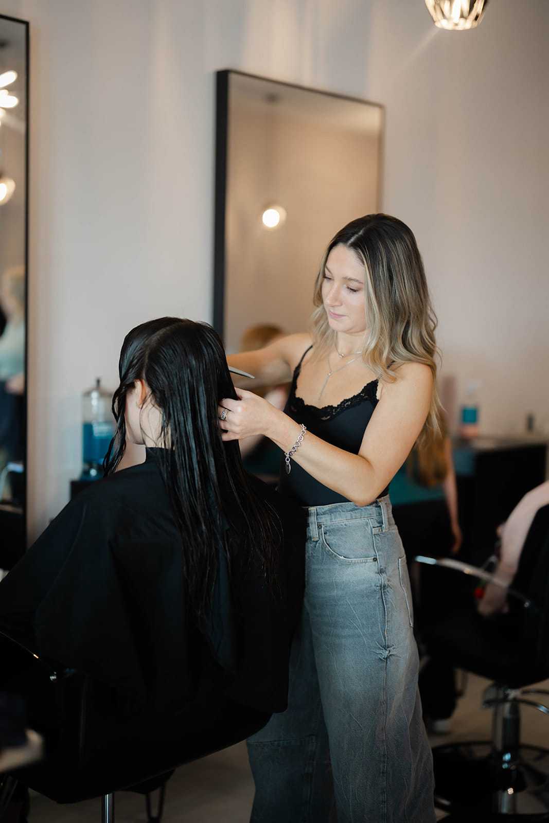 Hairdresser styling a customer's wet hair in a modern salon.