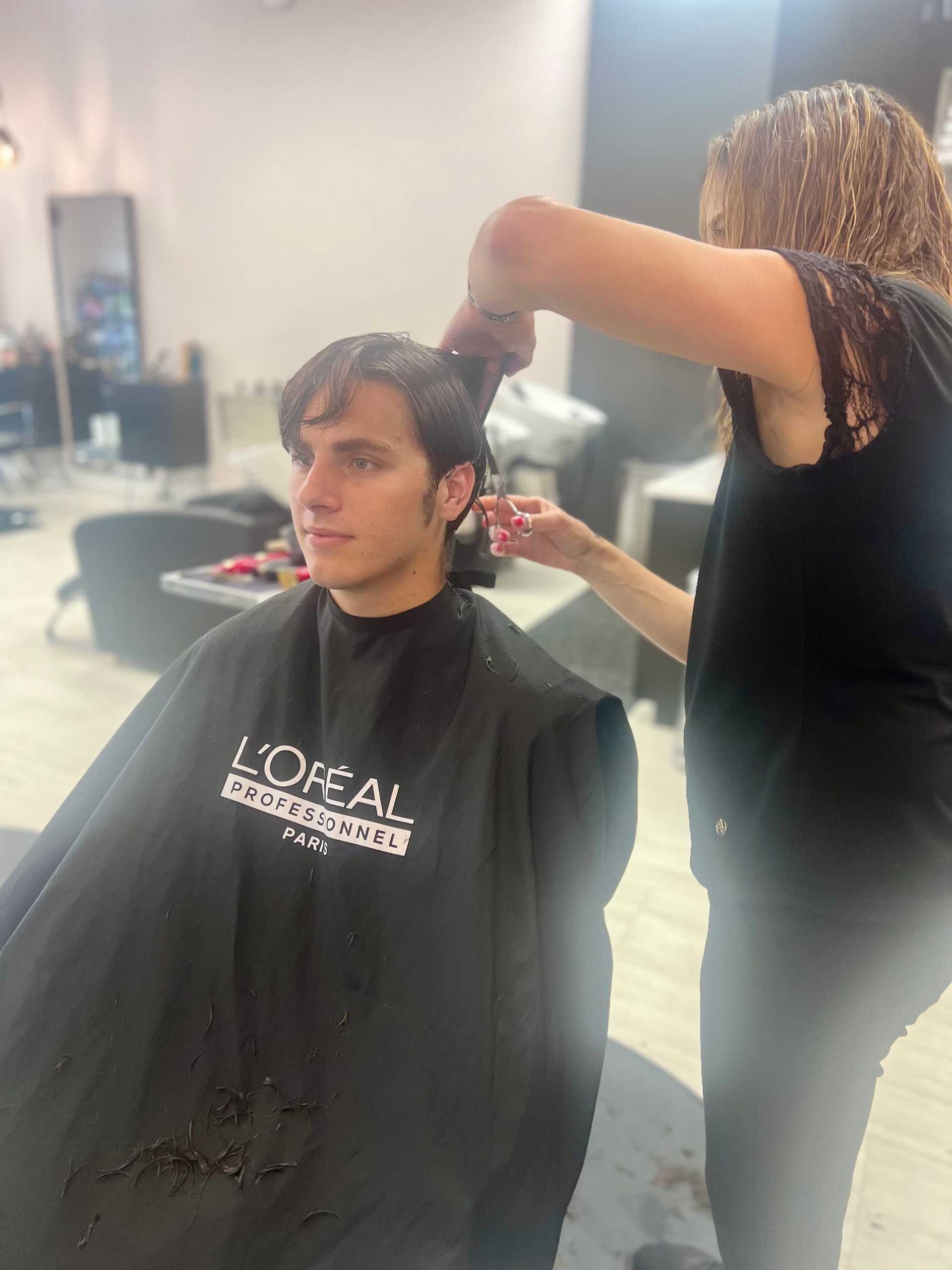 Man getting a haircut at a salon with L'Oréal smock.
