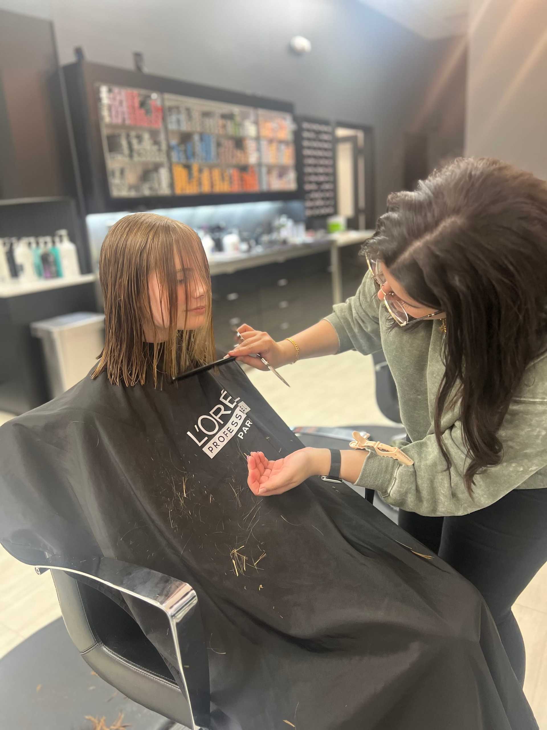 Person getting a haircut in a salon, stylist cutting wet hair in a modern setting.