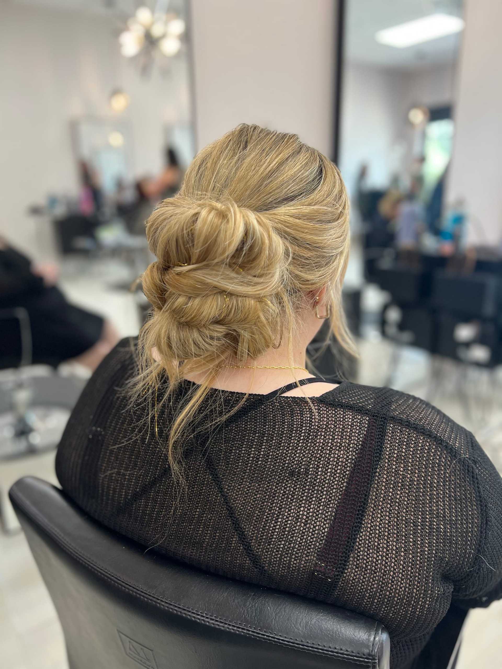 Woman with elegant braided updo hairstyle in a salon chair.