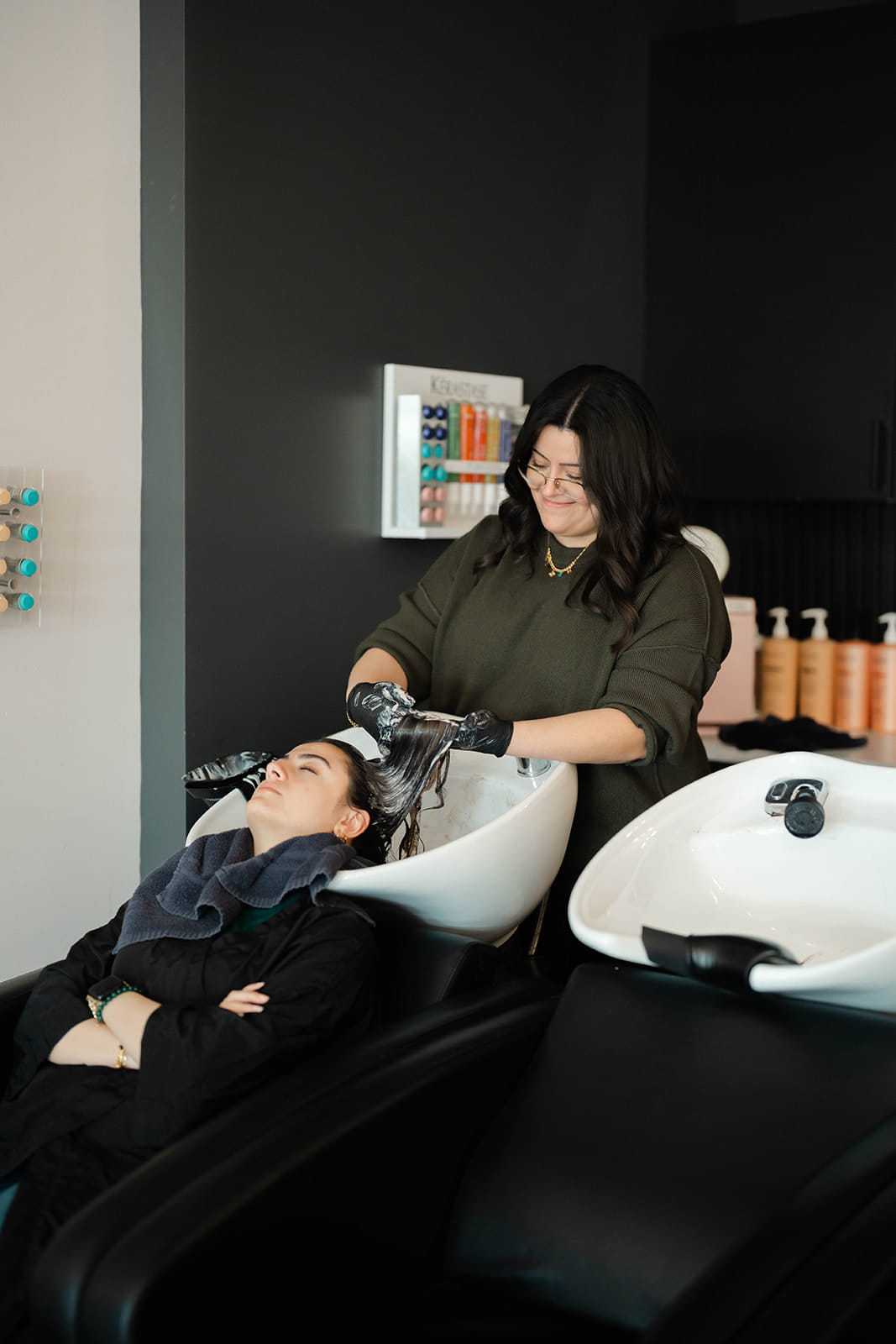 Hairdresser washing customer's hair in a salon sink.