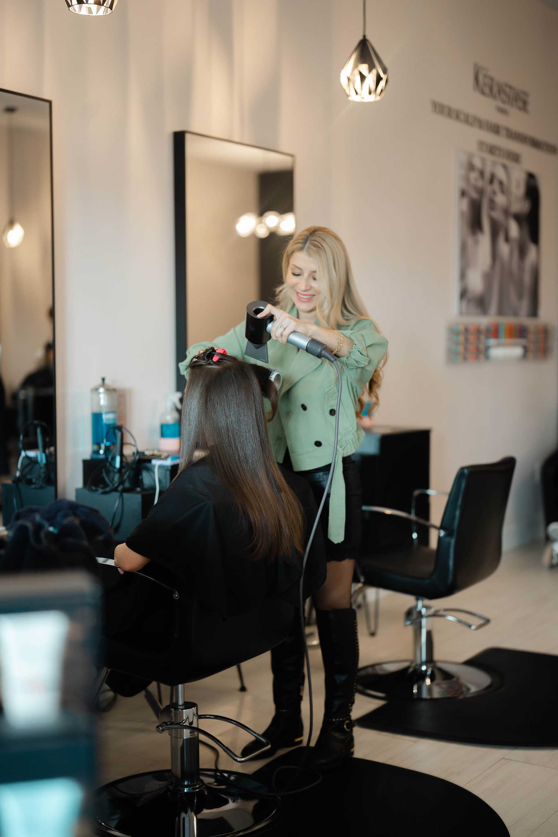 Hairstylist blow-drying client's hair in a salon.