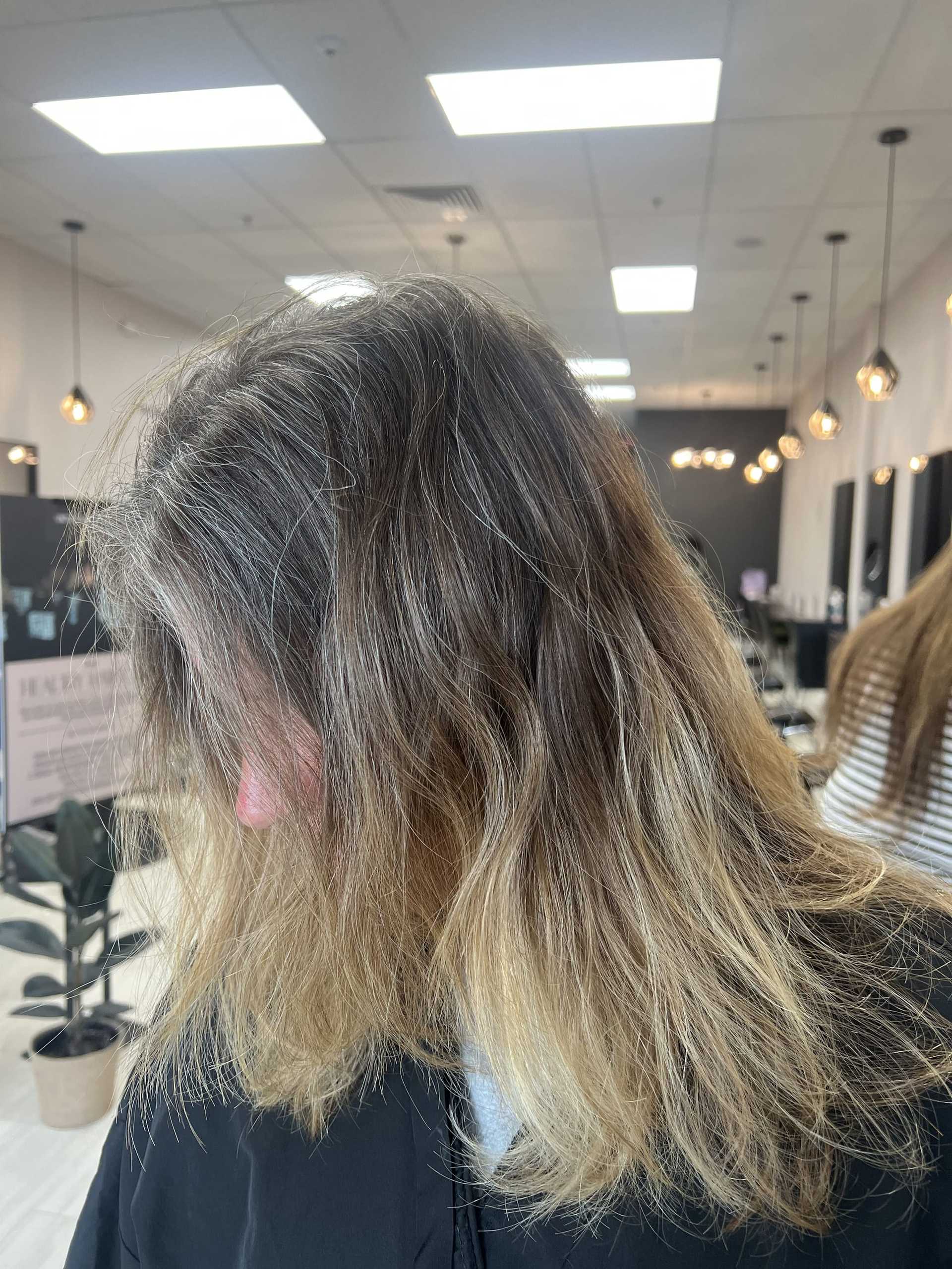 A woman with long, wavy blonde hair sits in a modern salon.