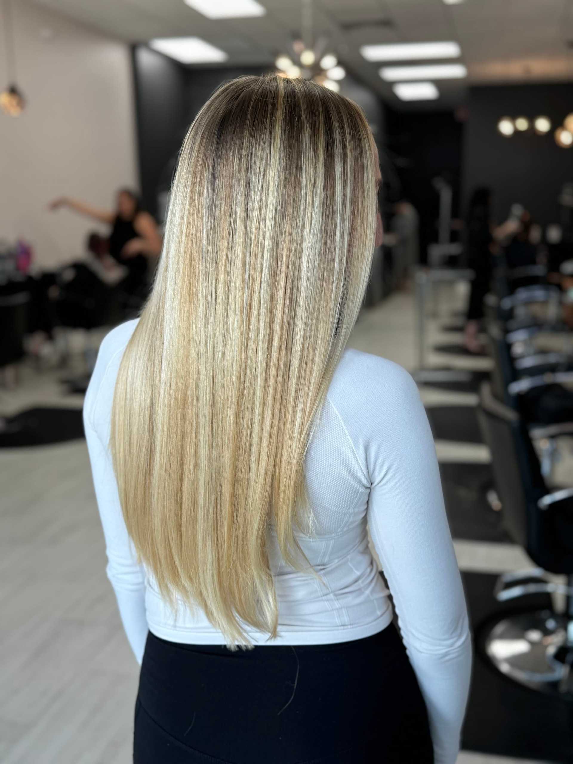 Long blonde hair with subtle highlights in a modern salon setting.