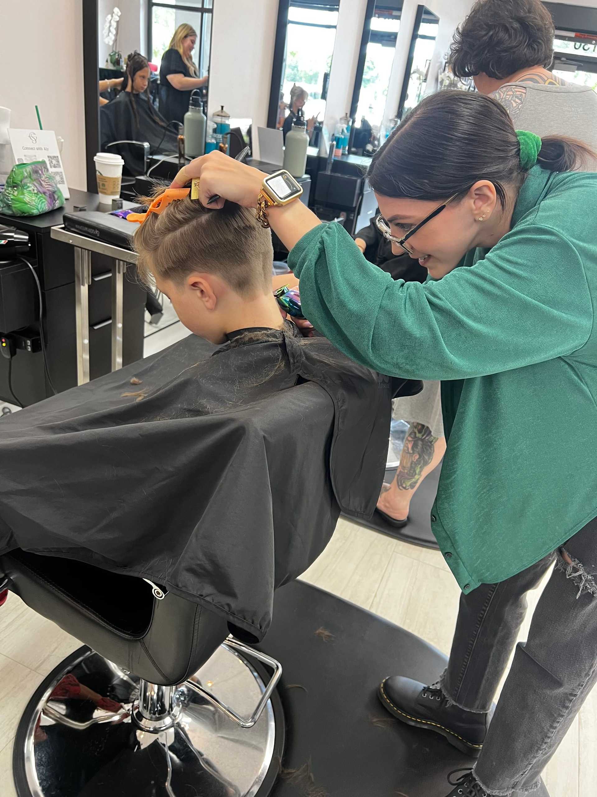 Hairdresser cutting a young boy's hair at a salon.