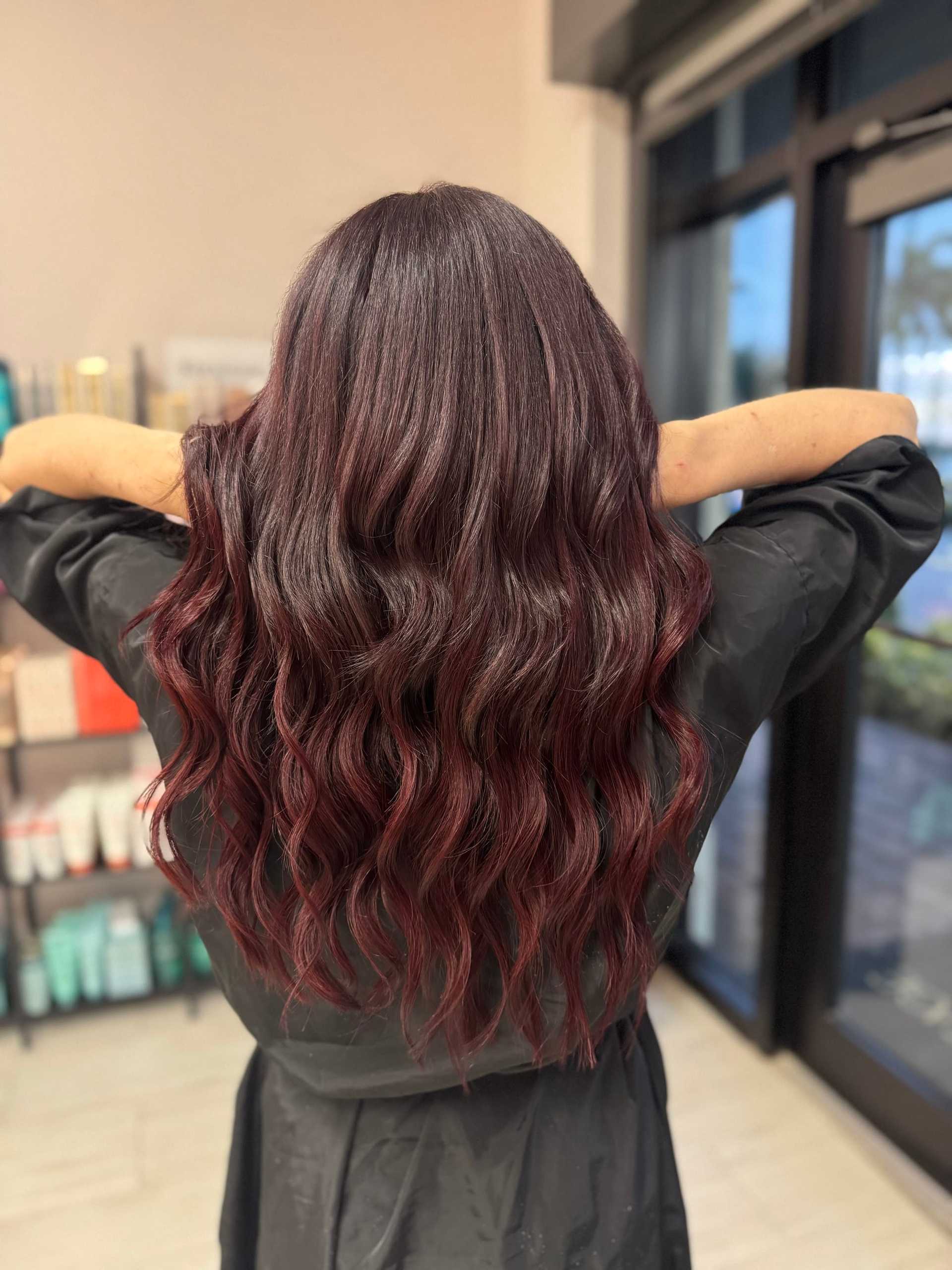 Wavy auburn hair from behind in a salon setting.